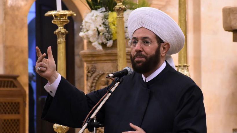 File photo showing Syria's then grand mufti, Ahmed Hassoun, speaking inside the Cathedral of Mar Elias in the northern Syrian city of Aleppo on 20 July 2020