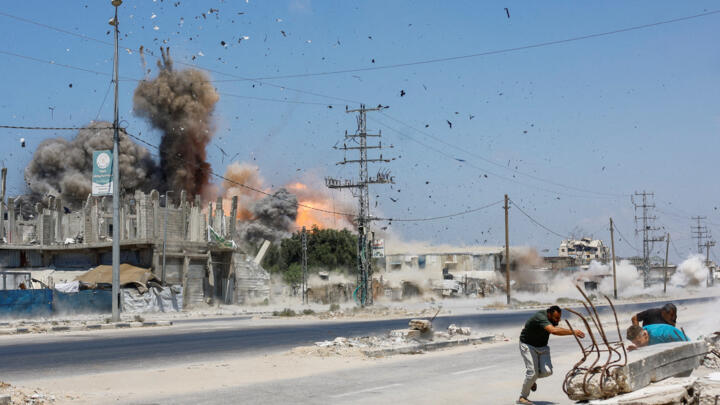 Des personnes courent se mettre à l'abri alors que des débris volent dans les airs, lors d'une frappe israélienne menée après que l'armée israélienne dans la zone d'Al-Zawayda.