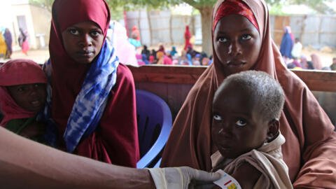 Un agent de santé mesure le périmètre brachial d'un bébé somalien au centre nutritionnel Feynuus, en périphérie de la capitale, Mogadiscio (Somalie), le 19 août 2026.
