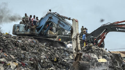 Des habitants et des secouristes utilisent une pelleteuse pour rechercher des corps après un éboulement survenu dans la nuit à la décharge de Dar-es-Salam, à Conakry, en Guinée, le 23 août 2026.
