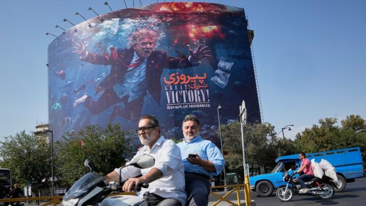 Motorcyclists pass a billboard depicting U.S. President Donald Trump underwater amid explosions, with the words "Great Victory! Strait of Hormuz," in Tehran, Iran, Monday, Aug. 24, 2026. (AP Photo/Vahid Salemi)