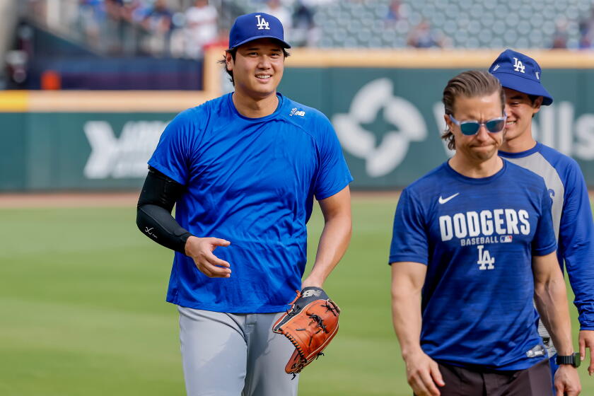 Los Angeles Dodgers pitcher Shohei Ohtani, left, walks off the field.