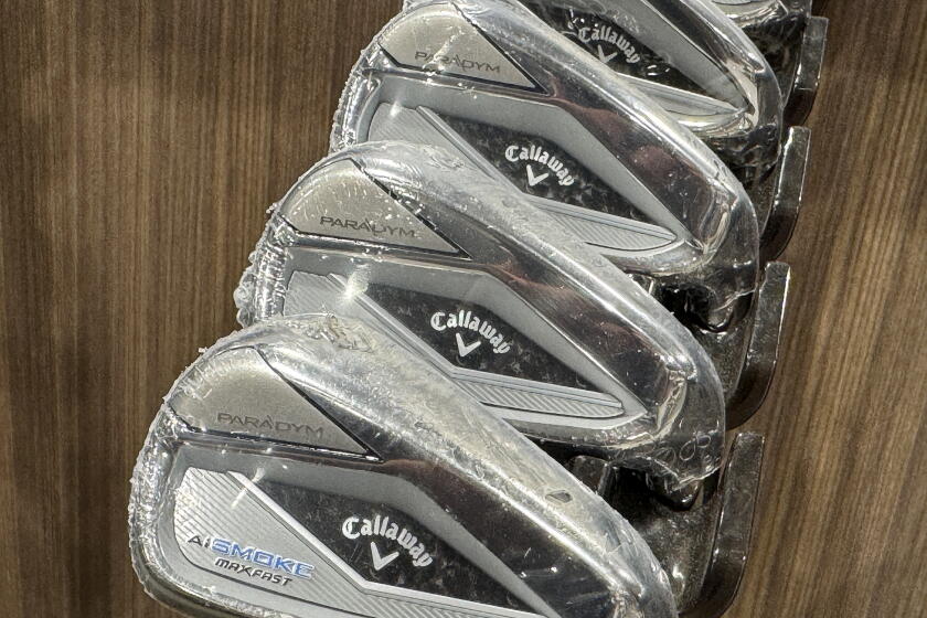 Callaway golf clubs hang from a store rack