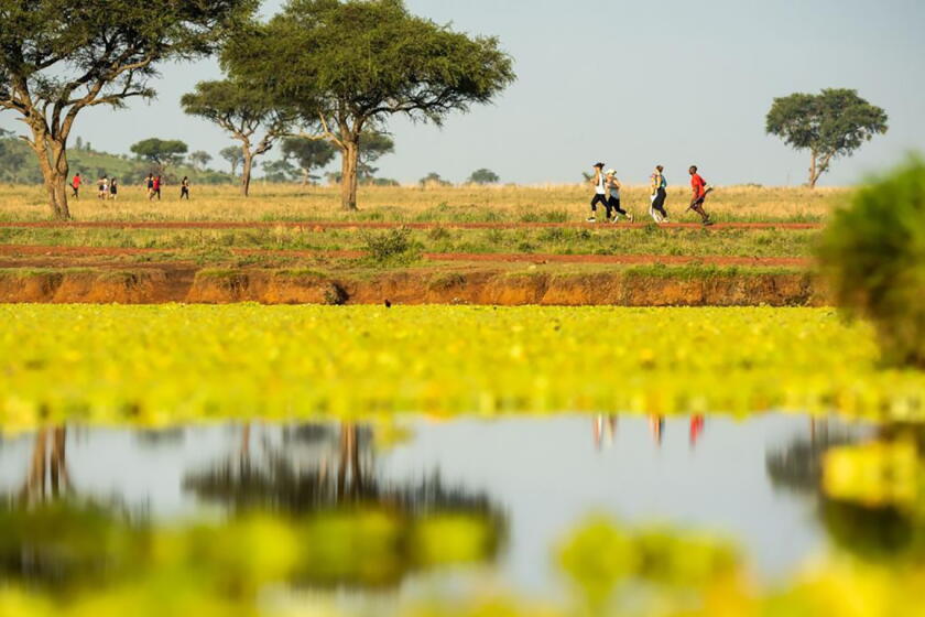 A group of women run across the African plain.