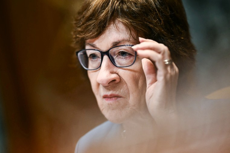 Susan Collins adjusts her glasses while seated