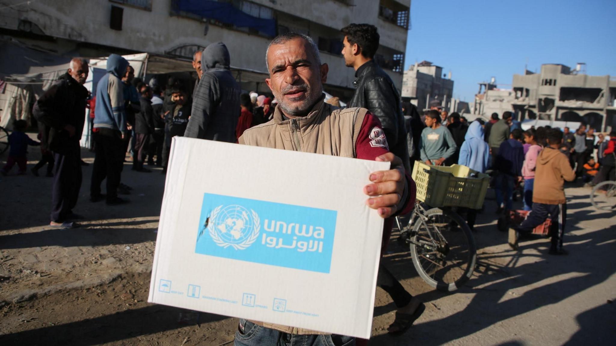 File photo showing a Palestinian man carrying an aid box provided by Unrwa, during a ceasefire between Hamas and Israel, in Khan Younis, southern Gaza (21 January 2025)