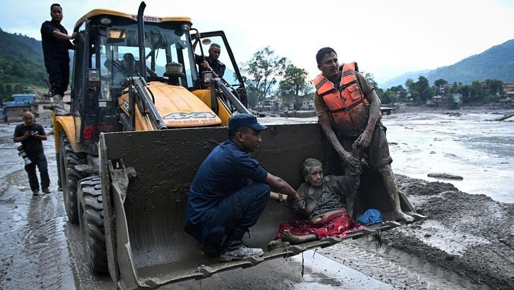 Elderly woman is evacuated from the site of a massive mudslide in Nepal using an excavator