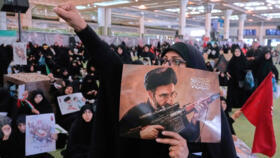 A mourner chants slogan as she holds a poster with graphic depicting Iran's Supreme Leader Ayatollah Mojtaba Khamenei at the Imam Khomeini Mosalla Grand Mosque in Tehran, July 14, 2026.
