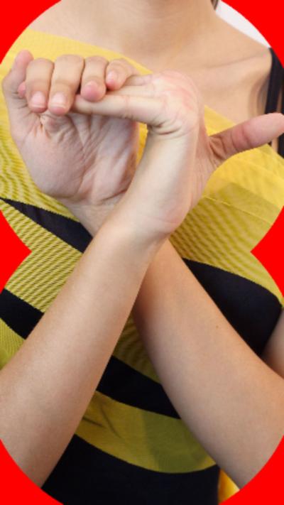 A person wearing a yellow and black striped tops bends the fingers on their hand back