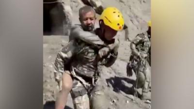 Two rescuers carry people on their backs