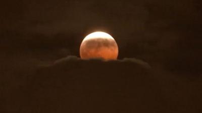 The Moon has a red tinge as it rises above clouds during the partial eclipse over Anaheim, California