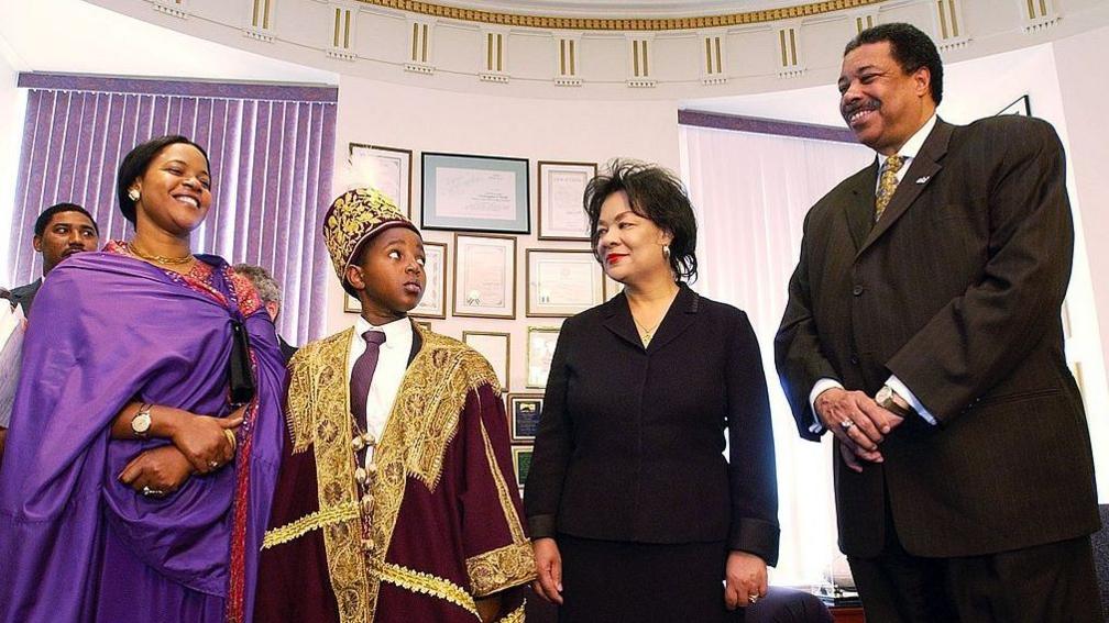 10-year-old King Oyo of the Kingdom of Toro in Africa, second from left, eyes Denver Mayor Wellington Webb, right, during an introductory meeting with the King's mother, Queen Mother Best Kemigisa Olimi, far left; and Denver First Lady Wilma Webb at the Denver City and County building Monday. The King, the youngest monarch in the world, is visiting Denver on a humanitarian mission for AIDS orphans in Uganda