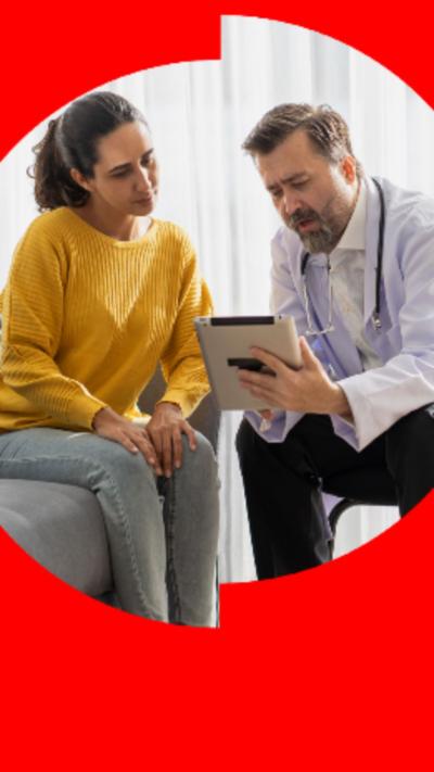 Woman in yellow jumper speaking to doctor holding iPad
