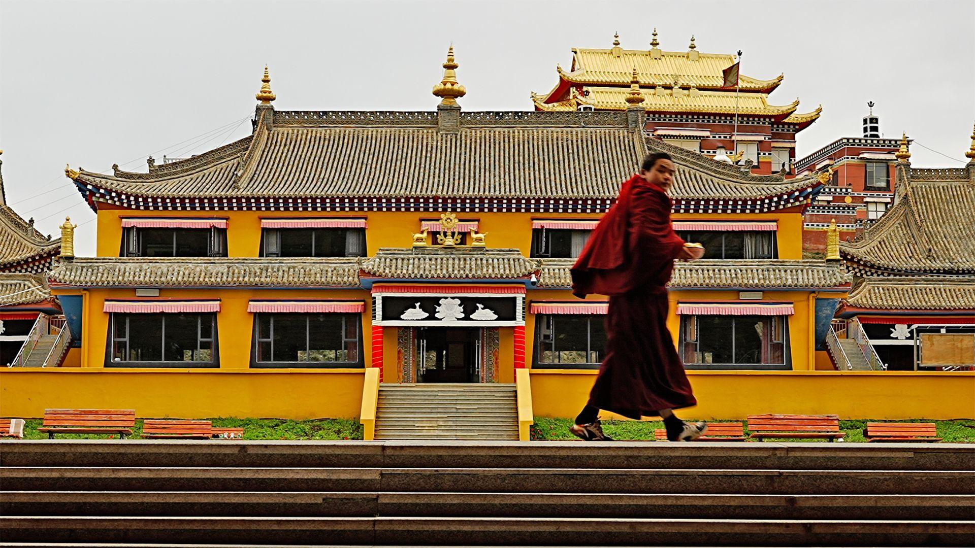 A monk walks across a courtyard at Langcuo Ma Monastery