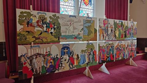 Panels from the Hastings Embroidery are displayed inside Hastings Town Hall, showing embroidered scenes including historical figures, ships, landscapes and events from different periods of history.