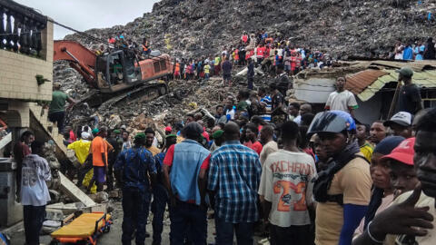 Des habitants et des secouristes utilisent une pelleteuse pour rechercher des corps après un glissement de terrain qui s'est produit pendant la nuit du 23 août 2026 à la décharge de Dar es Salaam, à Conakry.