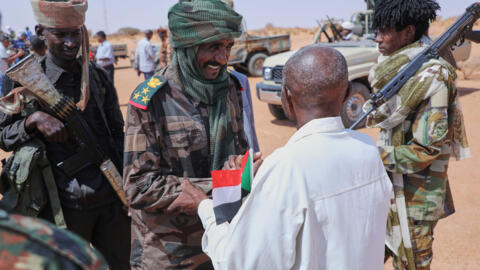 Moussa Khamsine, des Forces de soutien rapide (FSR), au centre, accueilli par un responsable du gouvernement soudanais, à l'ouest d'Omdurman, aux abords de Khartoum, au Soudan, le 19 août 2026.