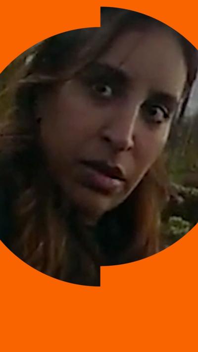 A woman with long brown hair looks at someone off-camera