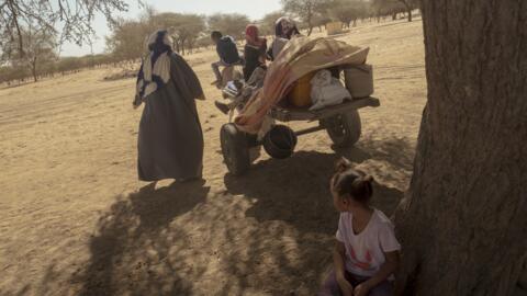 [Image d'archives] Une femme fuyant Leré, au Mali, portant ses enfants et ses affaires près de Fassale, le 4 novembre 2025.