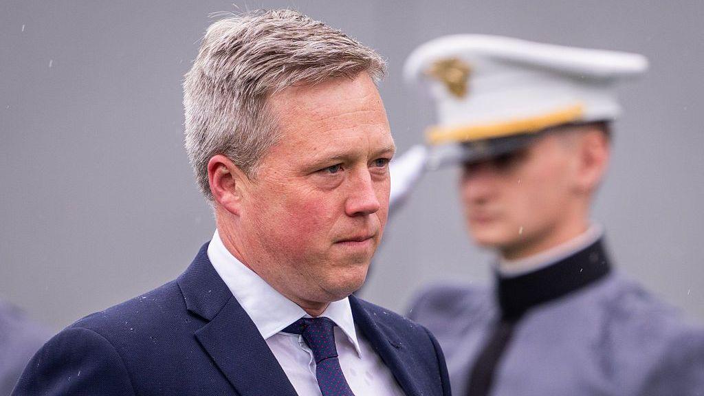 Secretary of the Army Dan Driscoll arrives for the United States Military Academy commencement ceremony in Michie Stadium at West Poin in New York as a service member salutes behind him. 