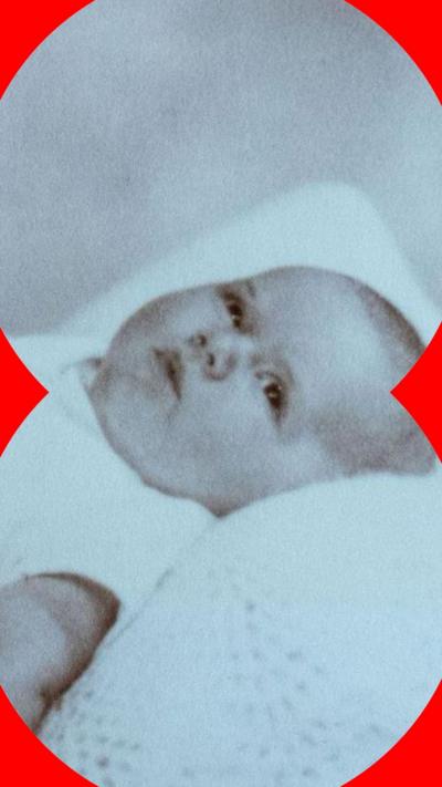 A photograph of a baby dressed in white and lying on white blanket
