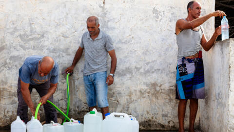 À Nabeul, en Tunisie, dimanche 30 août 2026, des habitants remplissent des bouteilles et des récipients avec de l'eau potable fournie par le propriétaire d'un puits, alors que la ville est en proie à une crise de l'eau et de l'électricité.