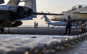 USS Abraham Lincoln families press Navy leaders over sailors’ mental health A sailor signals to a fighter jet on an aircraft carrier flight deck at sunset.