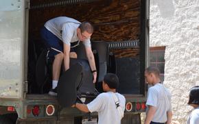 An airman hands another airman furniture from the back of a moving truck.