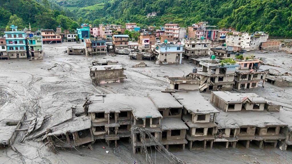 An aerial view shows houses lying deluged in sludge after flash floods at Devighat, Bidur Municipality in Nepal's Nuwakot district on August 27, 2026. Nepal's disaster agency said that 823 people remained out of contact on August 27, more than 24 hours after a deadly flood tore through the border region with Tibet. (Photo by Prabin RANABHAT / AFP via Getty Images)