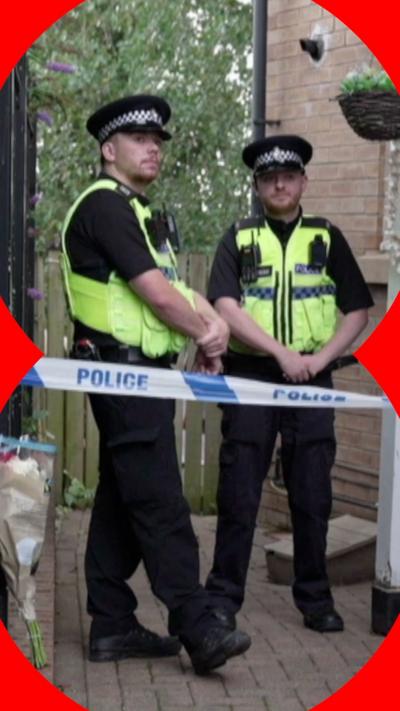Two police officers stand behind a cordon
