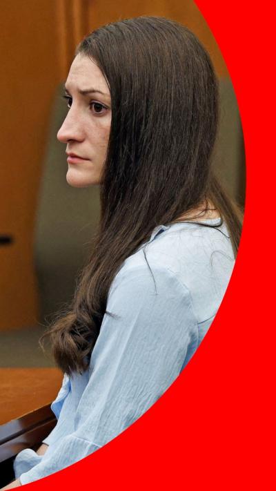 A woman with long brown hair sits in court
