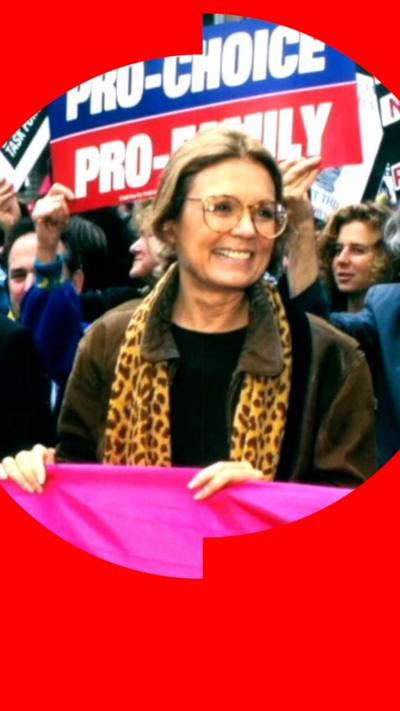 Gloria Steinem holds a pink banner at a rally, behind her a placard says Pro Choice.