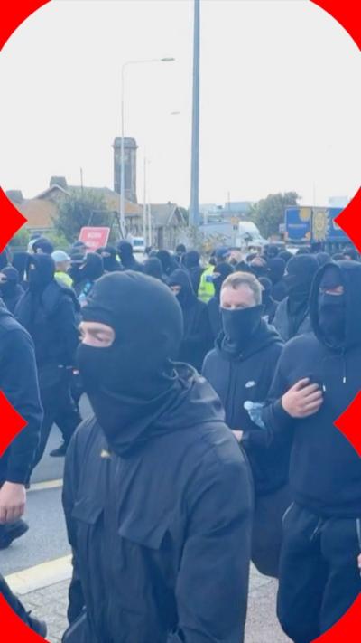 Masked protesters dressed in black walk through Dover