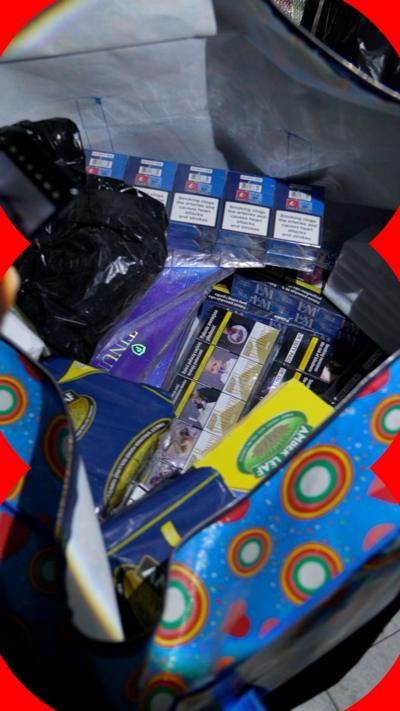 A bag stuffed with sleeves of illegal cigarettes found in the stock room of a shop in Inverness. Trading Standards offices are shining their torches into the bag.