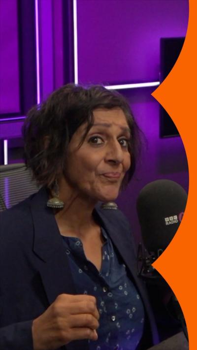 A woman with bobbed brown hair sits in front of a microphone