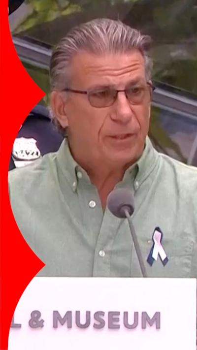 Man with grey hair and glasses stands at a podium