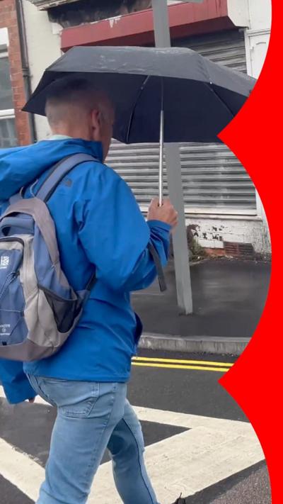Keith Girling wearing blue raincoat and holding black umbrella