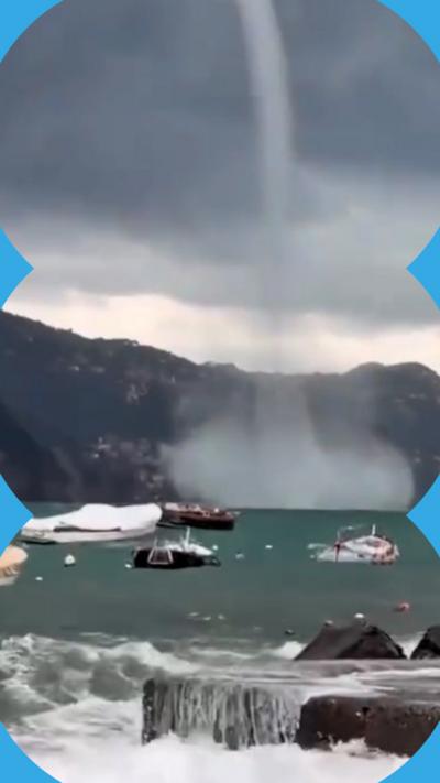 A powerful waterspout swirling over choppy coastal waters near small boats.