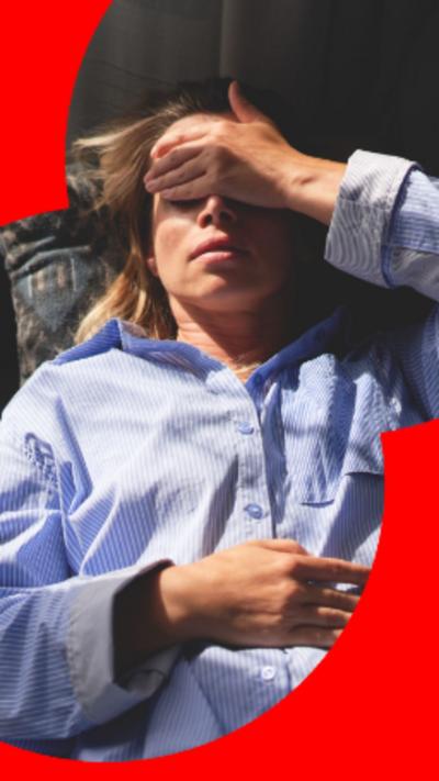 A woman living on her back with her left hand covering her eyes and forehead.