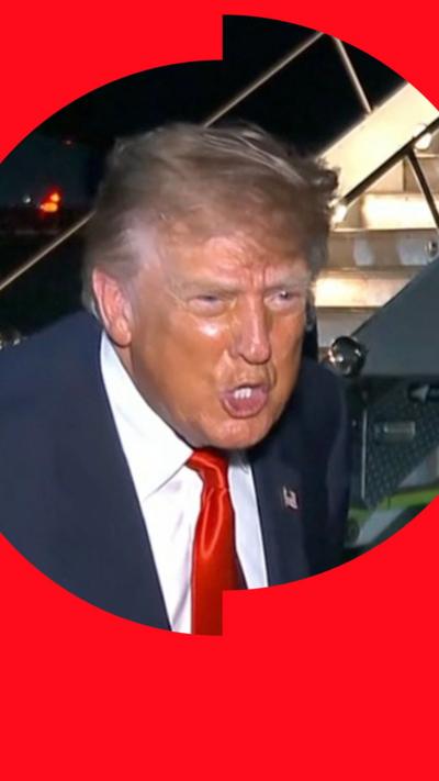 Donald Trump leaning in with an intense expression to talk to press.