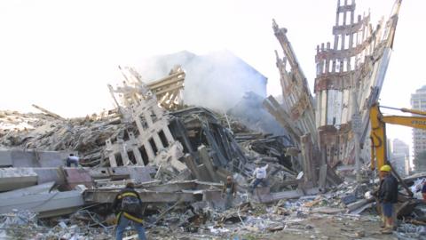 Rescue workers clear debris in the World Trade Center plaza after the September 11 2001 attacks in New York