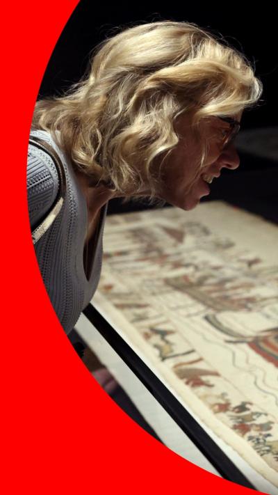 Blonde woman leaning over Bayeux Tapestry