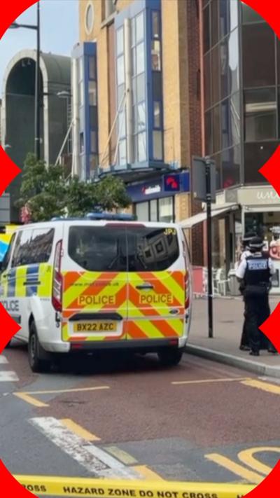 Police officers and a police van behind yellow cordon tape, near KFC on Bromley High Street.