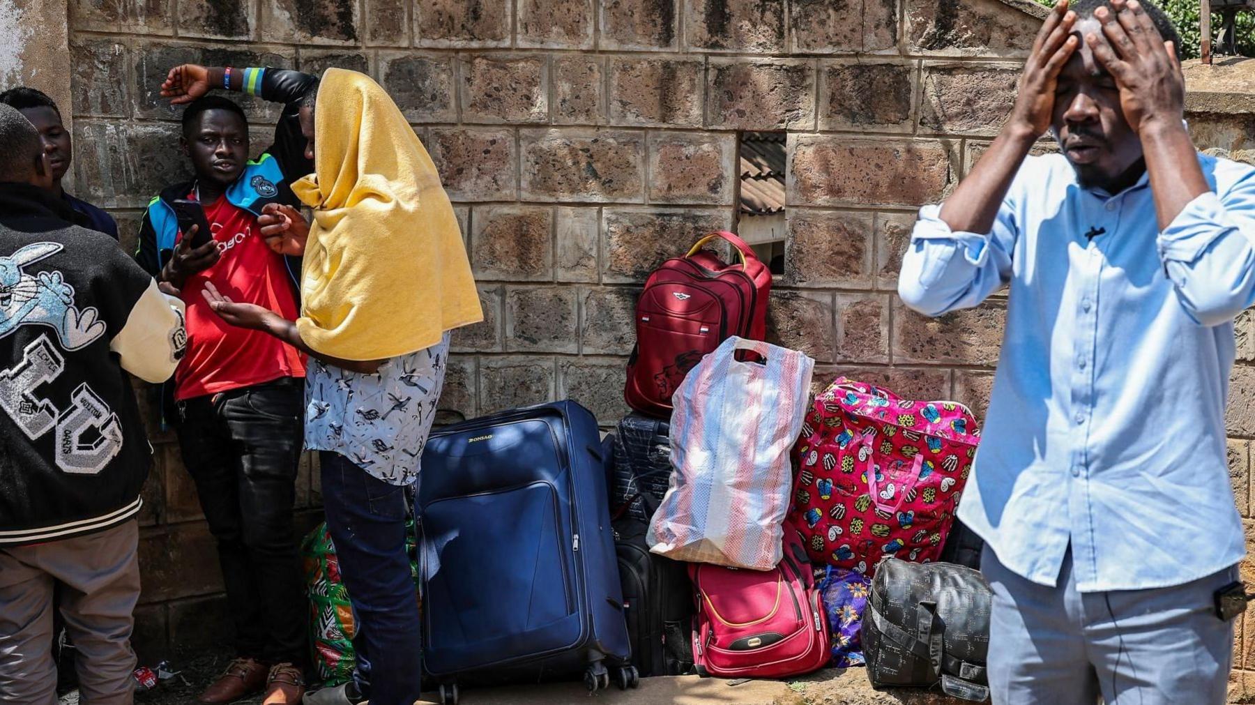 Burundian nationals, some with their belongings, gather at their embassy in Nairobi. A man on the right hold his hands to his face