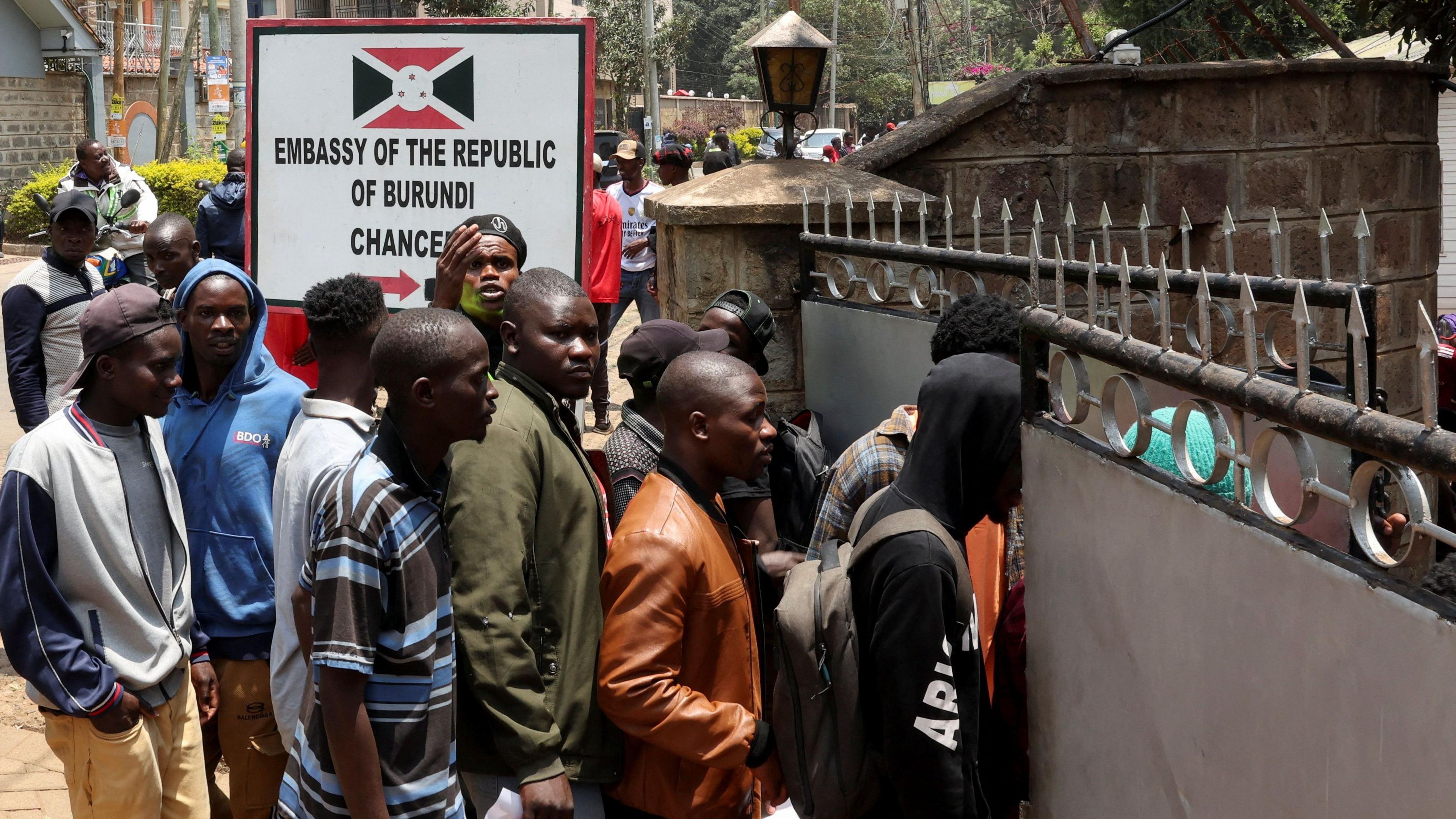 Line of people outside the embassy. there is a sign that reads Embassy of the Republic of Burundi