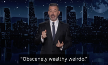 A man stands on a talk show stage. The caption at the bottom reads, "Obscenely wealthy weirdo."