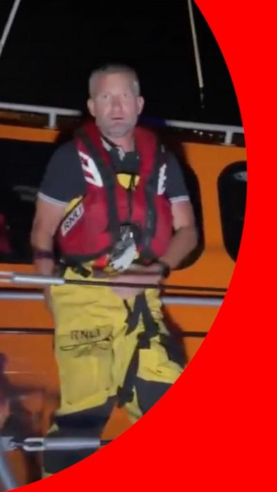 RNLI volunteer Neil wears a life vest standing on a life boat