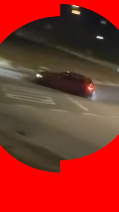 A car speeding at night, veering across lane markings