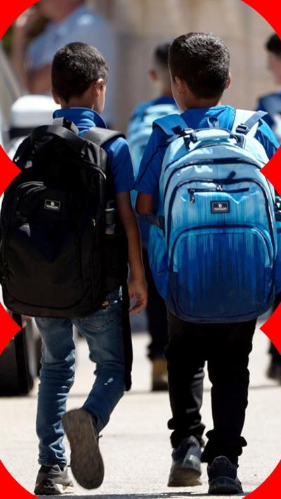 Palestinian kids walk to school. They are wearing blue school uniforms.