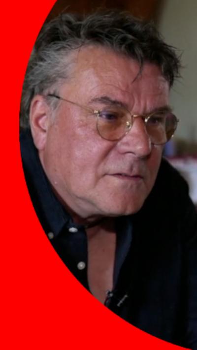 A man with short hair and glasses wearing a black shirt.